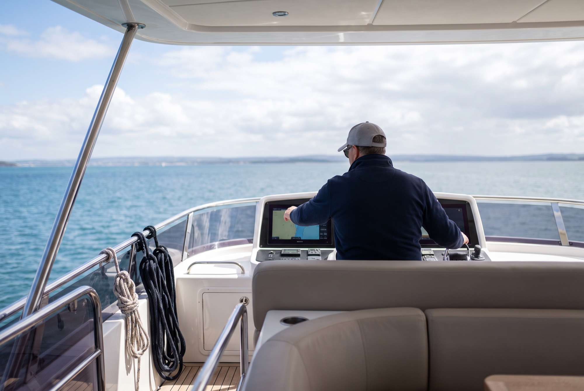 A skipper seen from behind checking the route on a flybridge chartplotter