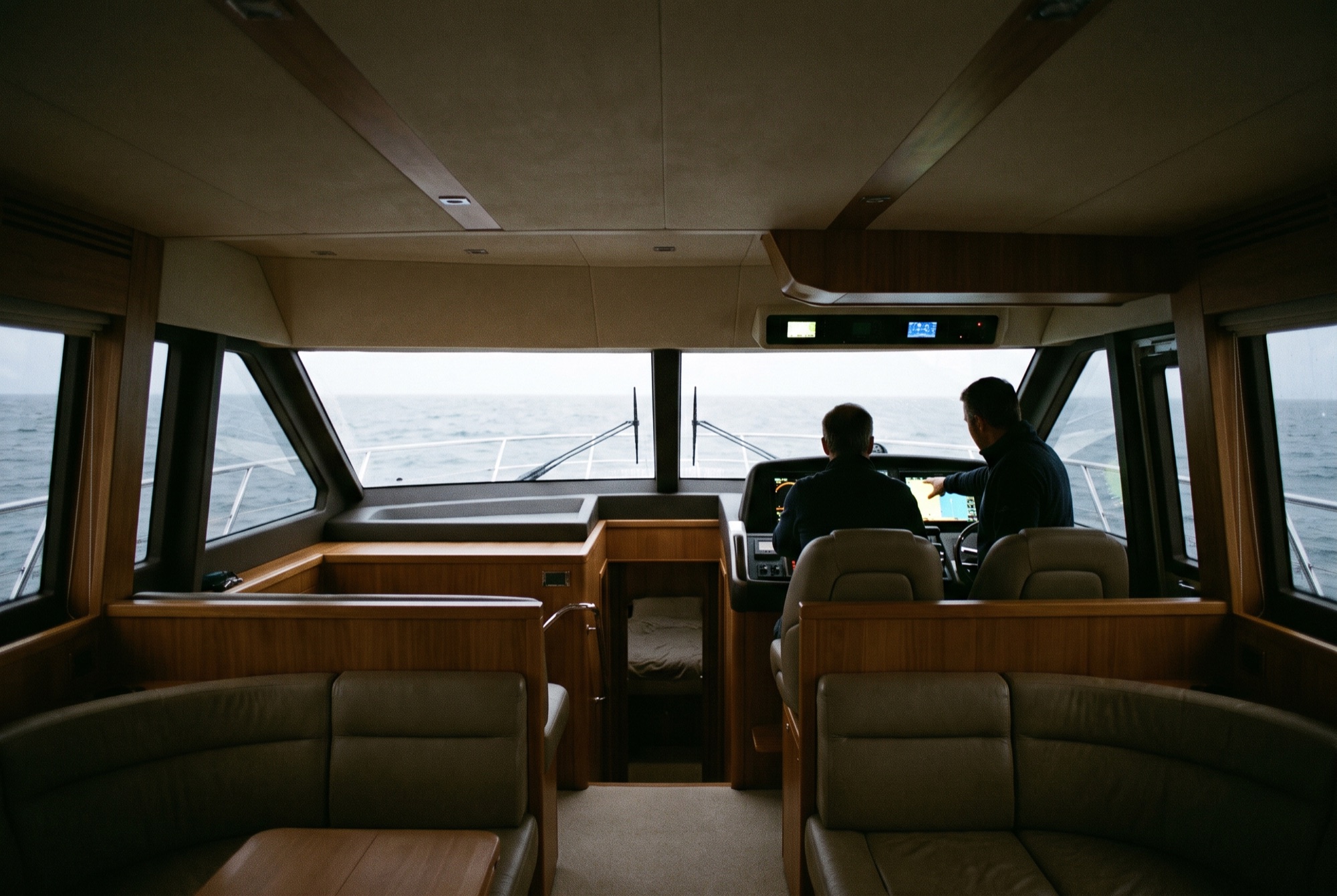 An owner and instructor at the lower helm of a motor yacht, seen from the saloon